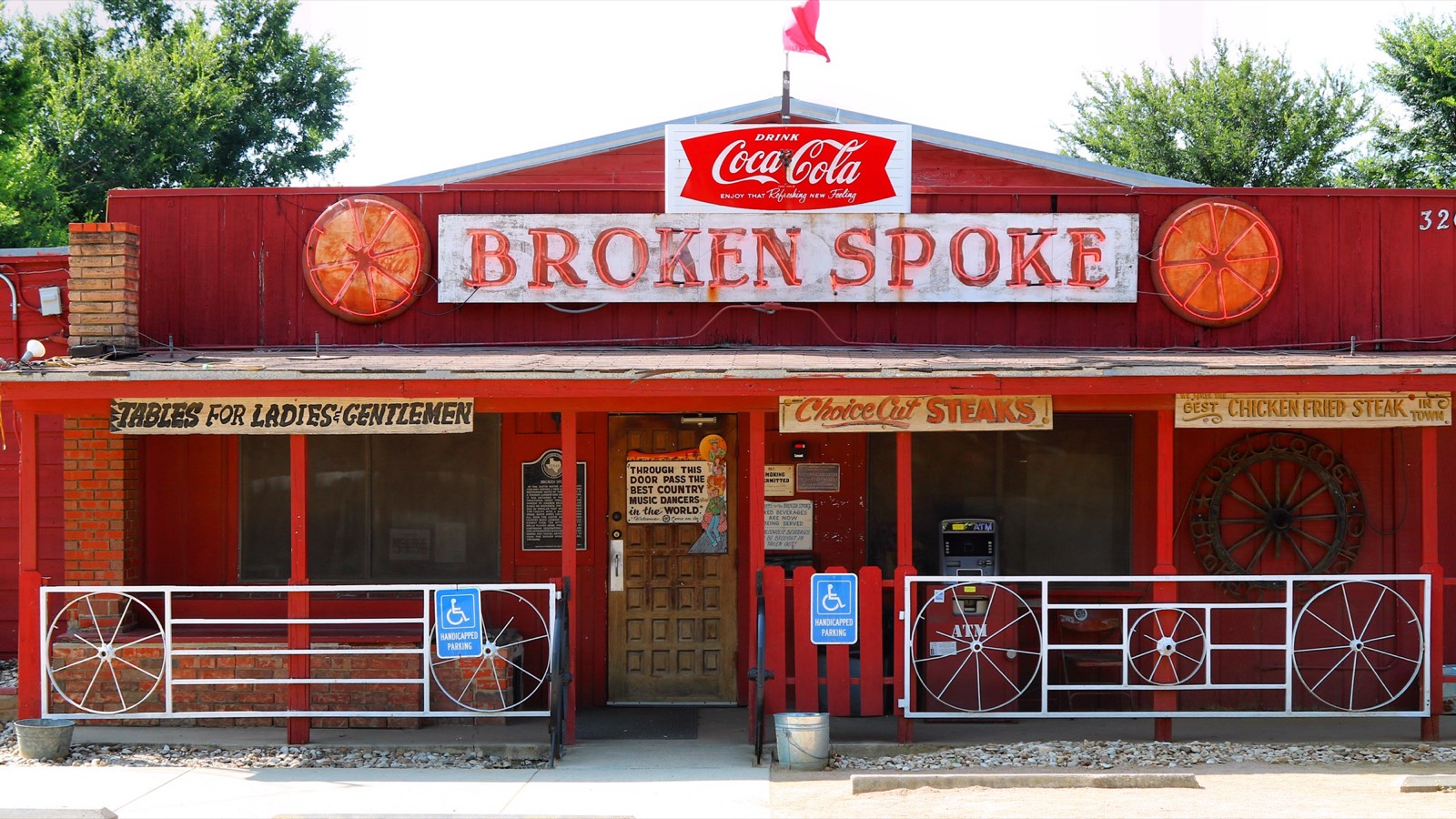 The Broken Spoke's storefront with wagon wheel neon signs and the Coca-Cola sign