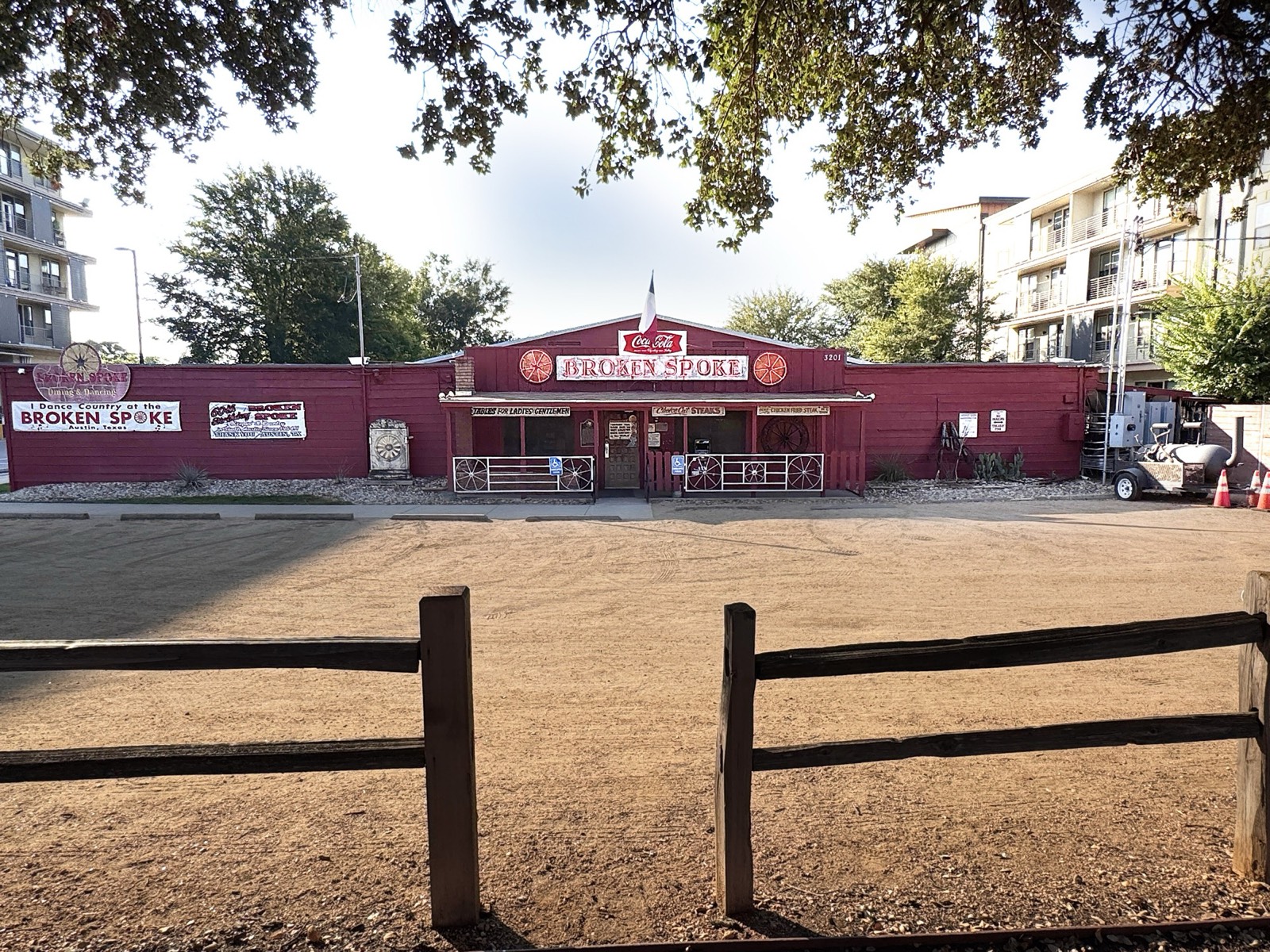 The Broken Spoke's low red building with apartment blocks rising behind it