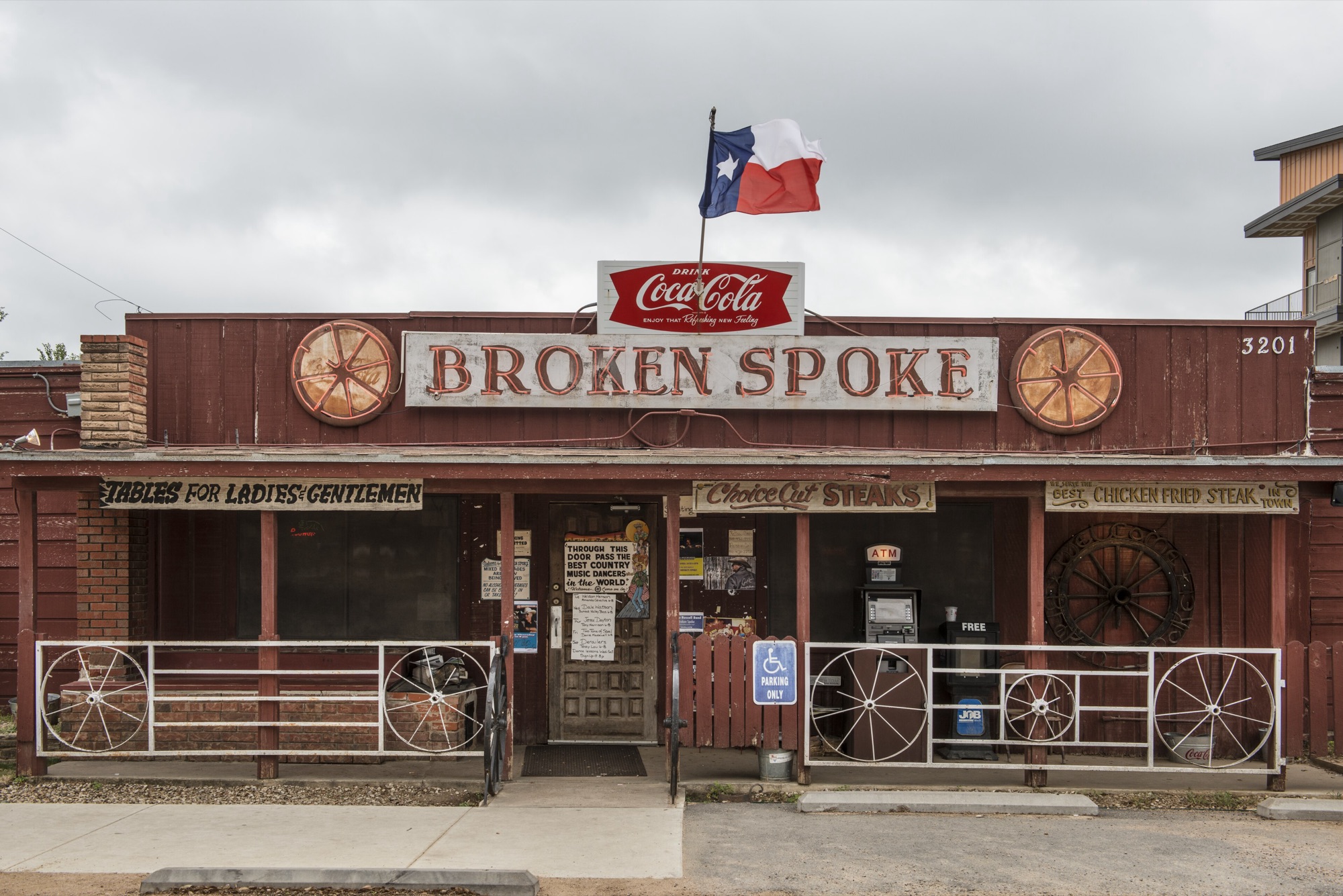 The Broken Spoke's front, with its sign, wagon wheels and Coca-Cola sign