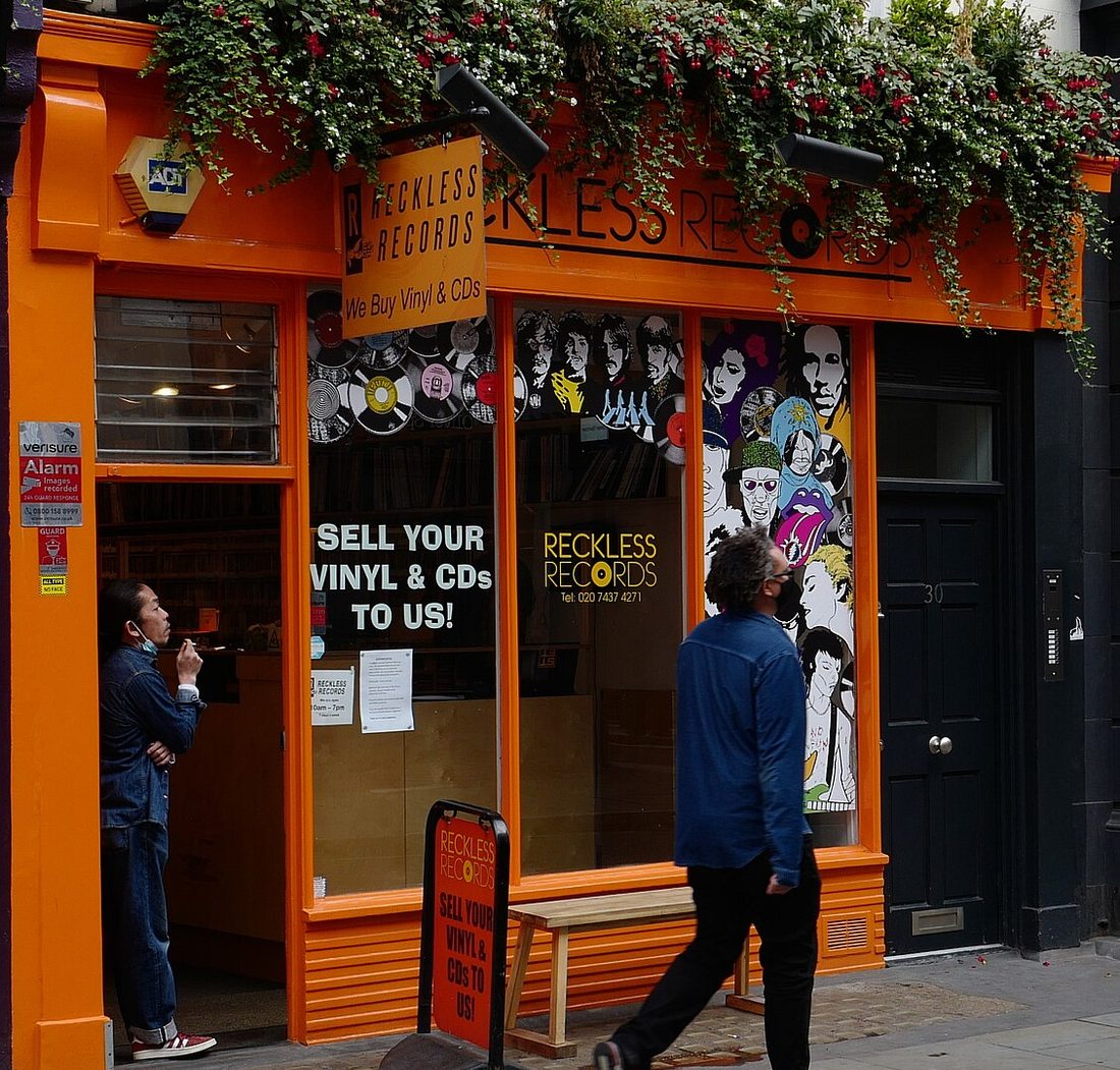 The orange Reckless Records storefront on Berwick Street in Soho, London, with 'Sell your vinyl and CDs to us' in the window