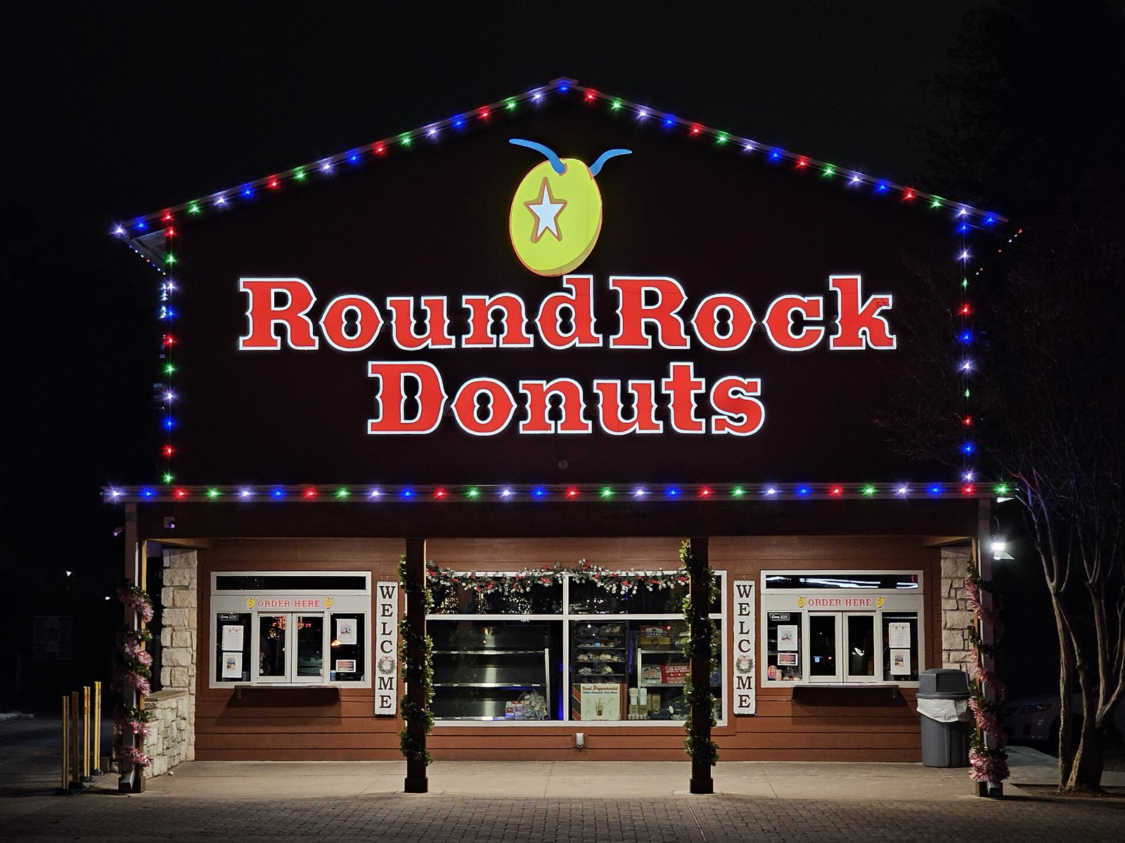 The Round Rock Donuts drive-thru at night, lit up with colored string lights